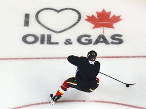 Calgary Flames skate at the Saddledome in Calgary Thursday, January 10, 2019. A new on ice sign has been painted in two of the corners supporting oil and gas.