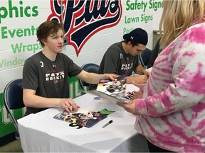 Steven Zonneveld, left, of the Regina Pats signs autographs for fans after Tuesday's 5-2 loss to the Calgary Hitmen at the Brandt Centre.