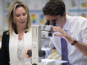 Kirsten Marcia, president and CEO of DEEP Earth Energy Production Corporation, explains about a sample of a porous sand stone from the deadwood formation which was drilled at 3400 meters deep to Prime Minister Justin Trudeau as he looks through a microscope at the Subsurface Geological Laboratory in Regina.  This is Canada's first geothermal power facility.