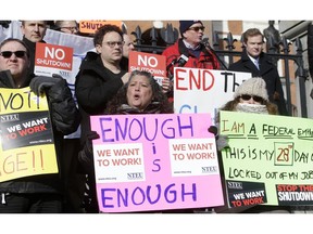 Internal Revenue Service employees, front row from the left, Brian Lanouette, of Merrimack, N.H., Mary Maldonado, of Dracut, Mass., and Maria Zangari, of Haverhill, Mass., display placards during a rally by federal employees and supporters, Thursday, Jan. 17, 2019, in front of the Statehouse, in Boston, held to call for an end of the partial shutdown of the federal government.
