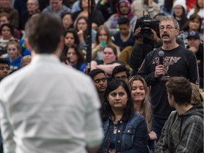 A man asks a question while Prime Minister Justin Trudeau speaks at a town hall at the University of Regina.