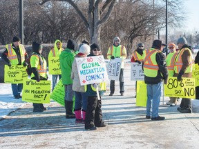 People stand across from the Saskatchewan Legislative Building in early December taking part in a so-called "yellow vest" protest against such things as Canada's federally imposed carbon tax and Canada signing the UN global pact on migration.