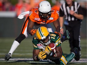 Edmonton Eskimos' Cory Watson (18) makes a reception as B.C. Lions' Chris Rwabukamba defends during the first half of a pre-season CFL football game in Vancouver, B.C., on Friday June 19, 2015.