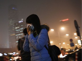 A woman covers her face with a mask as she rushes to a subway station on a heavily polluted day in Beijing on Tuesday, Dec. 8, 2015.