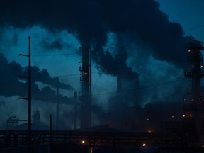 Emissions from a refinery rise into the sky at dusk on a winter evening. Heavy emitters will eventually be able to buy carbon offsets from projects that sequester or otherwise reduce carbon.