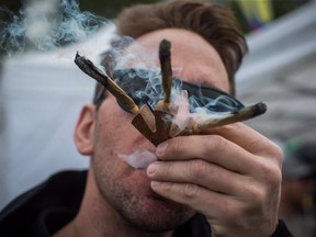 A man smokes three joints at once while attending the 4-20 annual marijuana celebration, in Vancouver, B.C., on Friday April 20, 2018.