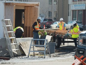 A crew works on the wooden, pedestrian walk-through at the corner of the Capital Pointe hole at the intersection of Albert Street and Victoria Avenue.