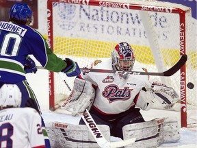 The Swift Current Broncos' Carter Chorney tries to knock the puck out of the in front of Regina Pats goalie Max Paddock in WHL action at the Brandt Centre on Wednesday.