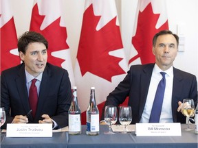 Prime Minister Justin Trudeau (left) sits next to Federal Finance Minister Bill Morneau during a round table discussion at the Canadian Transformational Infrastructure Summit in Toronto on Tuesday May 29, 2018.