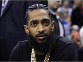 FILE - This March 29, 2018 file photo shows rapper Nipsey Hussle at an NBA basketball game between the Golden State Warriors and the Milwaukee Bucks in Oakland, Calif. Following a "Celebration of Life" at the same 21,000-seat arena where pop superstar Michael Jackson was memorialized 10 years ago, Hussle's body on Thursday, April 11, 2019, will be taken on a 25-mile funeral procession through many of the mean streets where he was raised and that he was trying to uplift when he was shot to death outside his Marathon Clothing store last month.