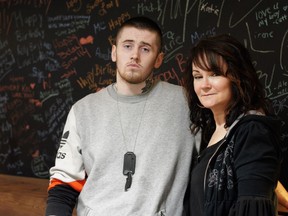 Marie Agioritis and her son Kayle Best stand in front of a blackboard covered in messages to her other son, Kelly Best, who died of a fentanyl overdose. Photo by Heidi Atter. For Hooked series.