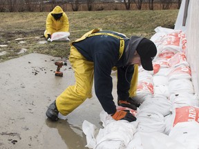 A man places a sandbag next to the foundation of a house in the town of Hudson, Que. west of Montreal, Friday, April 19, 2019.