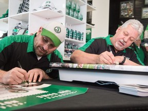 Saskatchewan Roughriders legends Bobby Jurasin, left, and Dave Ridgway sign autographs for fans Tuesday at Mosaic Stadium.