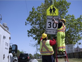 Shaun Gronick, left, and Tegan Sisco install a new 30/km hour speed sign at Glen Elm Community School in Regina.  The bylaw for the new speed comes into effect September 1, 2019.