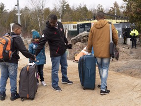 A family, claiming to be from Colombia, gets set to cross the border into Canada from the United States as asylum seekers on Wednesday, April 18, 2018 near Champlain, NY. The United Nations Refugee Agency says Canada admitted the largest number of resettled refugees last year and had the second highest rate of refugees who gained citizenship.
