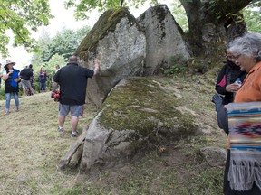 People gather around Lightning Rock following a ceremony of Indigenous leaders in a call to save one of Western Canada's First Nations burial site in Abbotsford, B.C., Friday, June 14, 2019.
