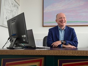 Saskatchewan Arts Board CEO Michael Jones sits in his office, at desk created by artist Brian Gladwell. The artworks on the walls are by Wally Dion (left) and Greg Hardy (behind).