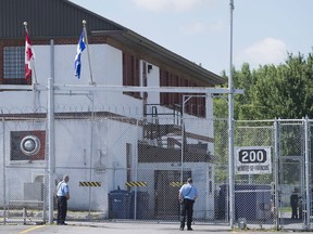 Guards stand outside the gates of an immigrant holding centre in Laval, Que., Monday, August 15, 2016.