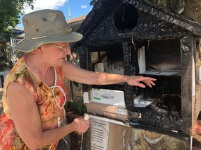 Darlene Krauss points out burned sections of the sidewalk library she and her husband installed on the edge of their property, called a Little Free Library. It was destroyed in a fire early on Canada Day.