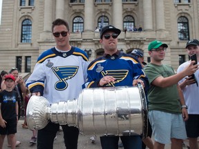 Jaden Schwartz, right, and Tyler Bozak of the Stanley Cup champion St. Louis Blues walk down the steps of the Saskatchewan Legislative Building displaying the Stanley Cup for excited fans below.