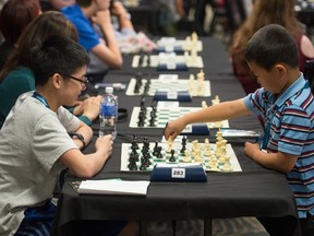 Michael Xu, right, and Tyler Tanaka play a game of chess at the opening of the Canadian Youth Chess Championship (CYCC) being held at the Travelodge hotel on Albert Street.
