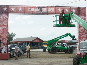 A crew works to set up  signage for the Country Thunder music festival.