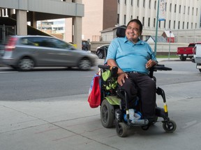 Jamie Mckenzie sits on the sidewalk on McIntyre street near Regina City Hall as traffic rushes by behind. A longtime user of Regina Paratransit, Mckenzie says the service cannot meet demand and is encouraging people with disabilities to use regular transit.