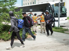 People get off a bus bringing Ontario wildfire evacuees to the University of Regina from the city's airport on July 11, 2019.