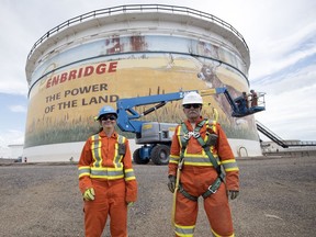 Artist Ashley Ridley, left, and Grant McLaughlin are some of the workers working to repainting the side of the Enbridge tank in Regina.