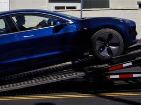A worker unloads a Tesla Inc. Model 3 electric vehicle from a car carrier outside the company's delivery centre in California.