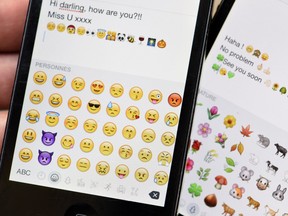 A picture shows emoji characters also known as emoticons on the screens of two mobile phones in Paris on August 6, 2015.