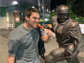 Saskatchewan Roughriders quarterback Cody Fajardo celebrates outside Mosaic Stadium and the George Reed statue by eating a corn dog after Thursday's 24-19 CFL victory over the Hamilton Tiger-Cats. Fajardo scored the game-winning touchdown with 24 seconds left.