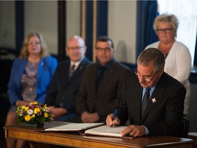 Lieutenant Governor Russell Mirasty, right, witnesses the signatures of three Saskatchewan cabinet ministers with new duties during a swearing in ceremony at Government House.