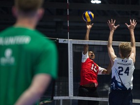 One of the Western Canada Summer Games' 2,000 volunteers looks on as Nunavut's Favour Omole and the Northwest Territories' Christopher Mathison, 24, compete in volleyball at the Innovation Credit Union iPlex.