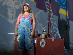 Artist Jamie Reynolds stands in front of a mural she is creating on a building on Montreal Street.