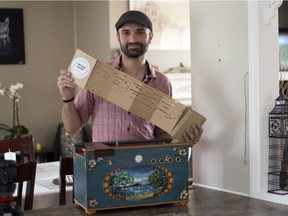 Cédric Delavaud holds a piece of perforated cardboard, the music for his barrel organ, at home in Regina.