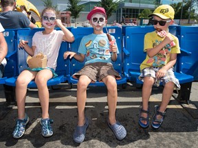 From left, Violet Morrison, Lex Morrison and Reeve Morrison enjoy some corndogs and poutine in the midway during the Queen City Ex held at Evraz Place in this file photo from Aug. 3, 2019. The QCX returns Friday after a hiatus due to the pandemic.