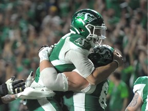 Saskatchewan Roughriders quarterback Cody Fajardo, left, celebrates after scoring the game-winning touchdown Thursday against the visiting Hamilton Tiger-Cats.