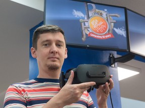 Ryan Hill holds a VR headset at the Regina Public Library, where Past 50/Future 50 is on view.