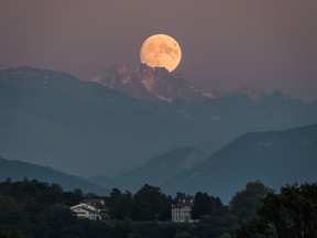 A near full moon rises behind The French Alps as seen from Geneva on September 12, 2019.