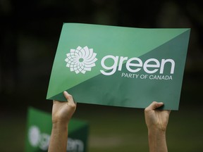 A supporter holds a sign for the Green Party of Canada in Toronto, Tuesday, Sept. 3, 2019. The federal Green party has accepted an election candidate's resignation over a social-media post in which he mused about sending pig meat to devotees of Muhammad.