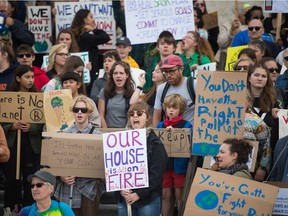 Climate change activists stand on the steps of the Saskatchewan Legislative Building during a rally taking place on Friday.