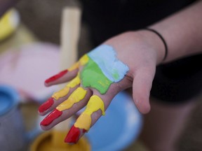 A young girl paints her hand the colours of the rainbow flag during Pride Week.