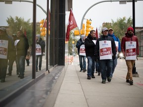 Unifor members walk a picket on Lorne Street near some buildings occupied by SaskTel.