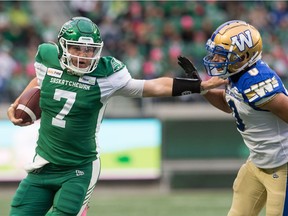 Saskatchewan Roughriders quarterback Cody Fajardo (7) stiff arms Winnipeg Blue Bombers defender Derek Jones during the first half of Saturday's game at Mosaic Stadium.