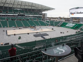 A crew works to install aluminum ice pans on which the ice surface for the Heritage Classic hockey game will be built at Mosaic Stadium.