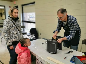 Jana Jedlic, left, watches with her daughter Liana Gomez as Repair Cafe volunteer Roy Dorwart attempts to fix her espresso machine. The Repair Cafe was held at the Cathedral Neighbourhood Centre on Saturday.