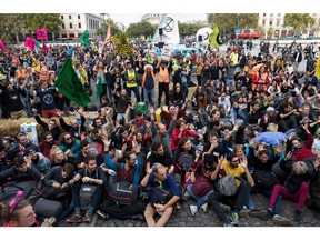 Protesters sit on the ground to block the Pont au Change bridge during a demonstration called by climate change activist group Extinction Rebellion, on October 7, 2019 in front of the Conciergerie in Paris. Climate protesters from Sydney to London blocked roads on October 7, sparking mass arrests at the start of two weeks of civil disobedience demanding immediate action to save the Earth from "extinction". The year-old group Extinction Rebellion has energized a global movement demanding governments drastically cut the carbon emissions that scientists have shown to cause devastating climate change.