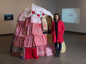 Artist Amalie Atkins stands next to a hut made of aprons, which is part of an exhibition of her work at the Art Gallery of Regina.