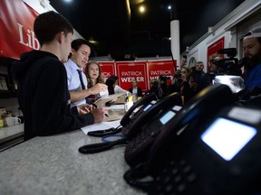 Liberal leader Justin Trudeau works with volunteers Nicola Cox and Christian Gomes as he makes a campaign stop at a riding office in West Vancouver, B.C., on Sunday Oct. 20, 2019.